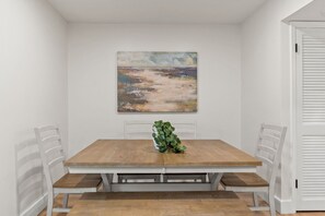 Ein Esstisch mit Bänken, ein Gemälde an der Wand und eine Tür mit Fensterläden.