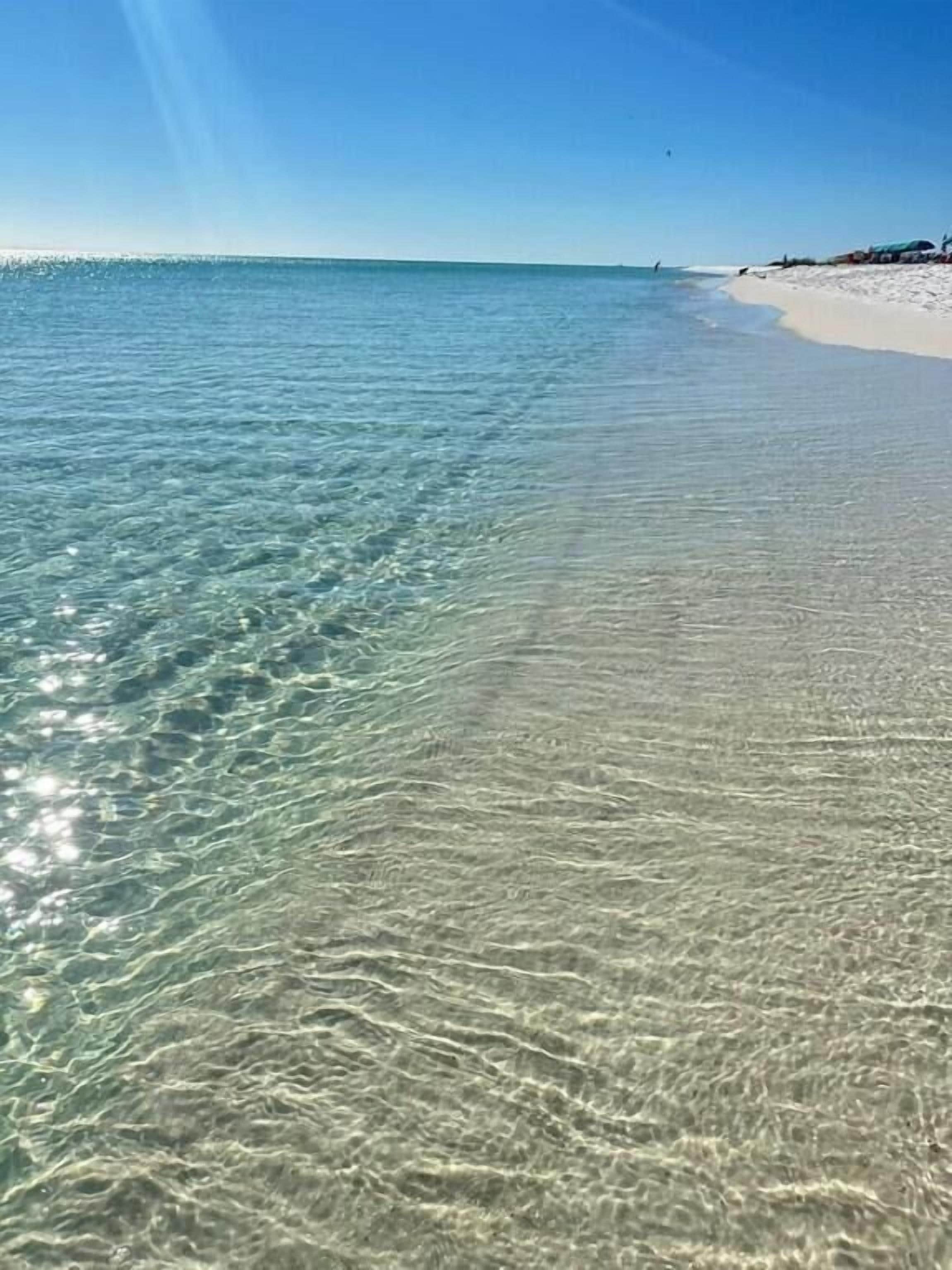 Una playa con aguas claras y poco profundas y una orilla arenosa.