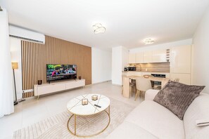 Ein modernes Wohnzimmer mit Flachbildfernseher, rundem Couchtisch und Sofa.
