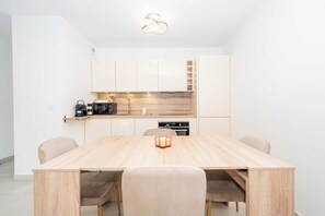 Eine moderne Küche mit weißen Schränken, einer Holz Arbeitsplatte und einem Esstisch mit Stühlen.