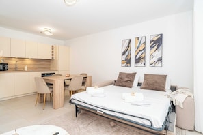Ein modernes, helles Schlafzimmer mit Bett, Nachttischen und einem Schreibtisch.