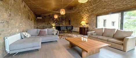 Um interior rústico com paredes de pedra, teto de madeira e uma área de estar com sofá e mesa de centro.