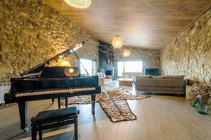 A room with a grand piano, a sofa, and a patterned rug. - Designed 16th-century farmhouse among open fields (Lérida)