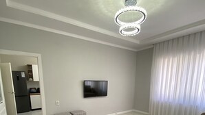 Un salon moderne doté d’un téléviseur à écran plat, d’un canapé, d’un coin repas avec un réfrigérateur et d’une cuisine.
