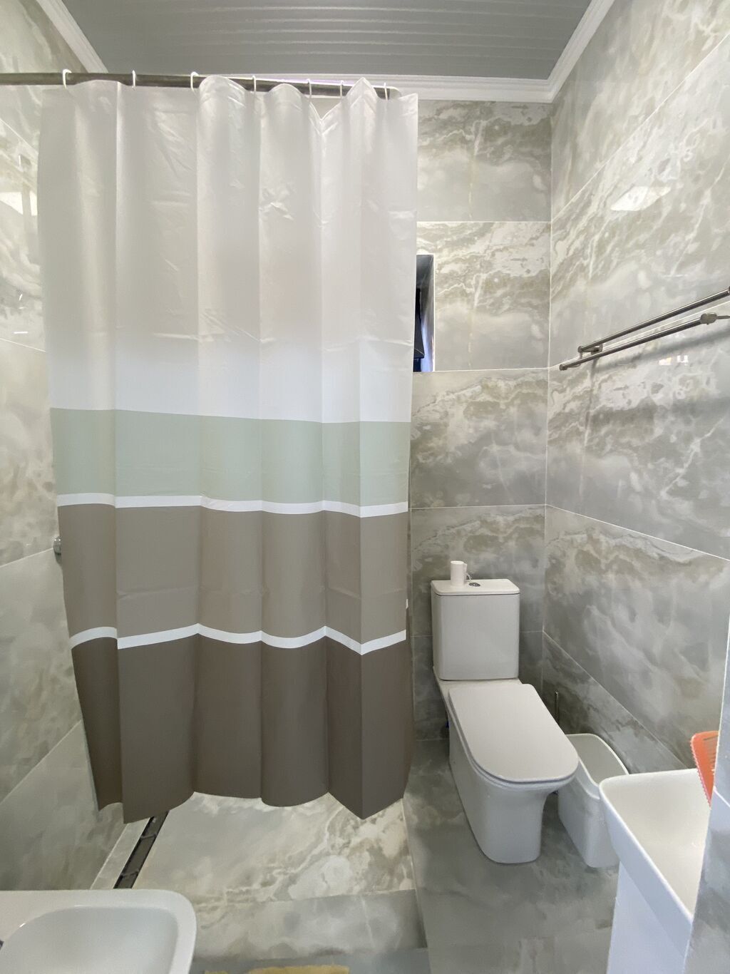 Une salle de bain avec un rideau de douche, des toilettes et un lavabo.