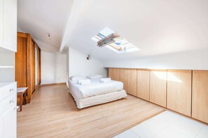 A modern bedroom with a skylight, wooden flooring, and a bed with white linens. - Bright & Central Duplex - Near the Eiffel Tower (Paris)