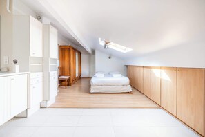 Ein Schlafzimmer mit einem Bett, einem Holzschrank und einem Oberlicht.