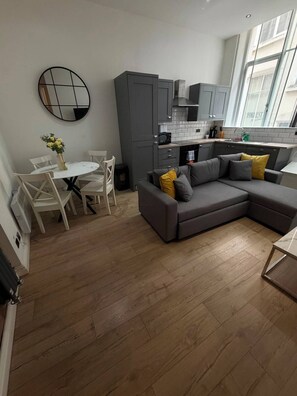 A modern kitchen with grey cabinets, a white tiled backsplash, and a window with a view. - Sweeting Street Apartment (Liverpool)