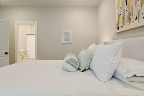 Un dormitorio con una cama grande, una puerta que da a un baño y un cuadro en la pared.