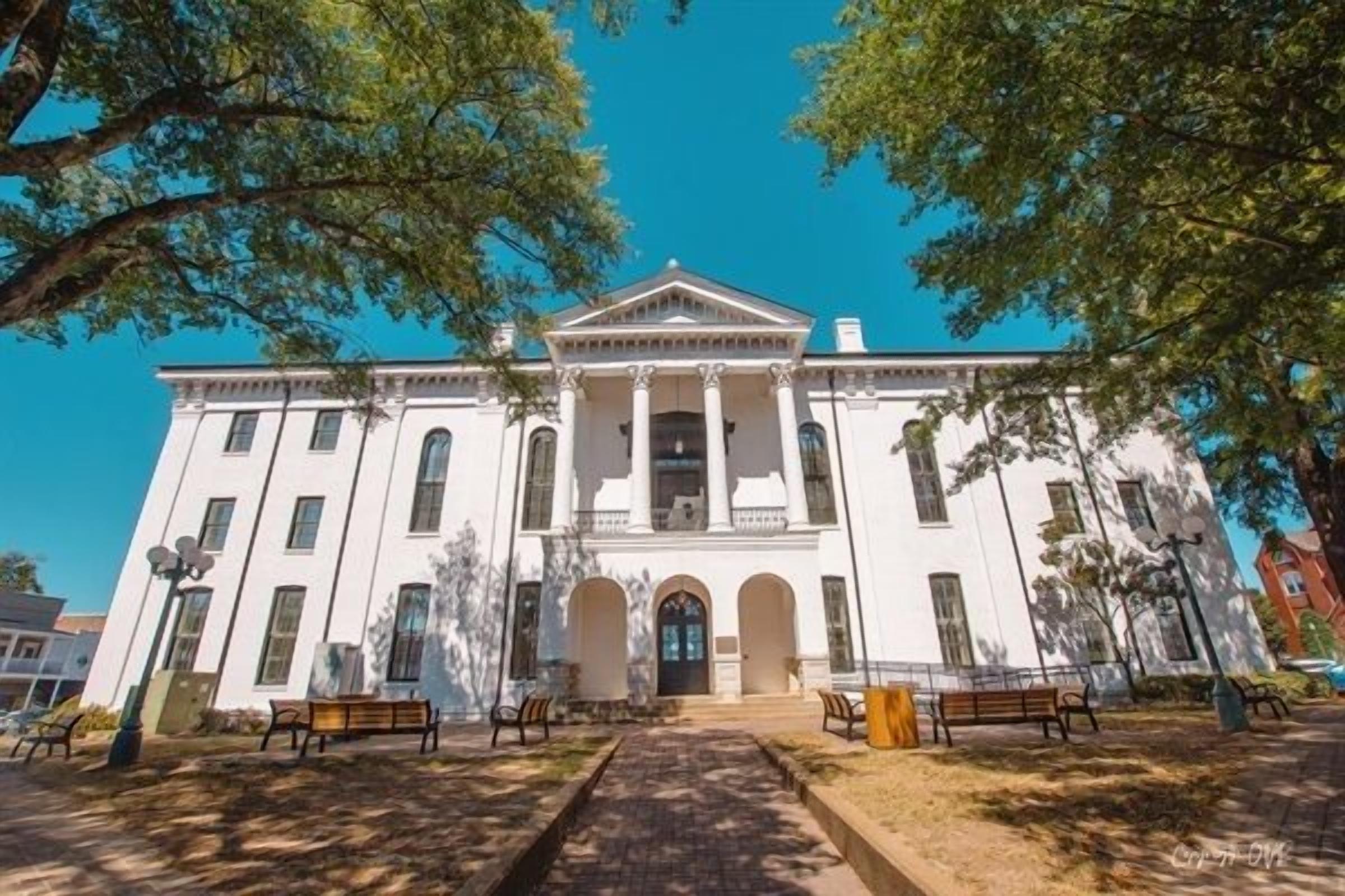 A large white building with a central entrance, columns, and a symmetrical facade.