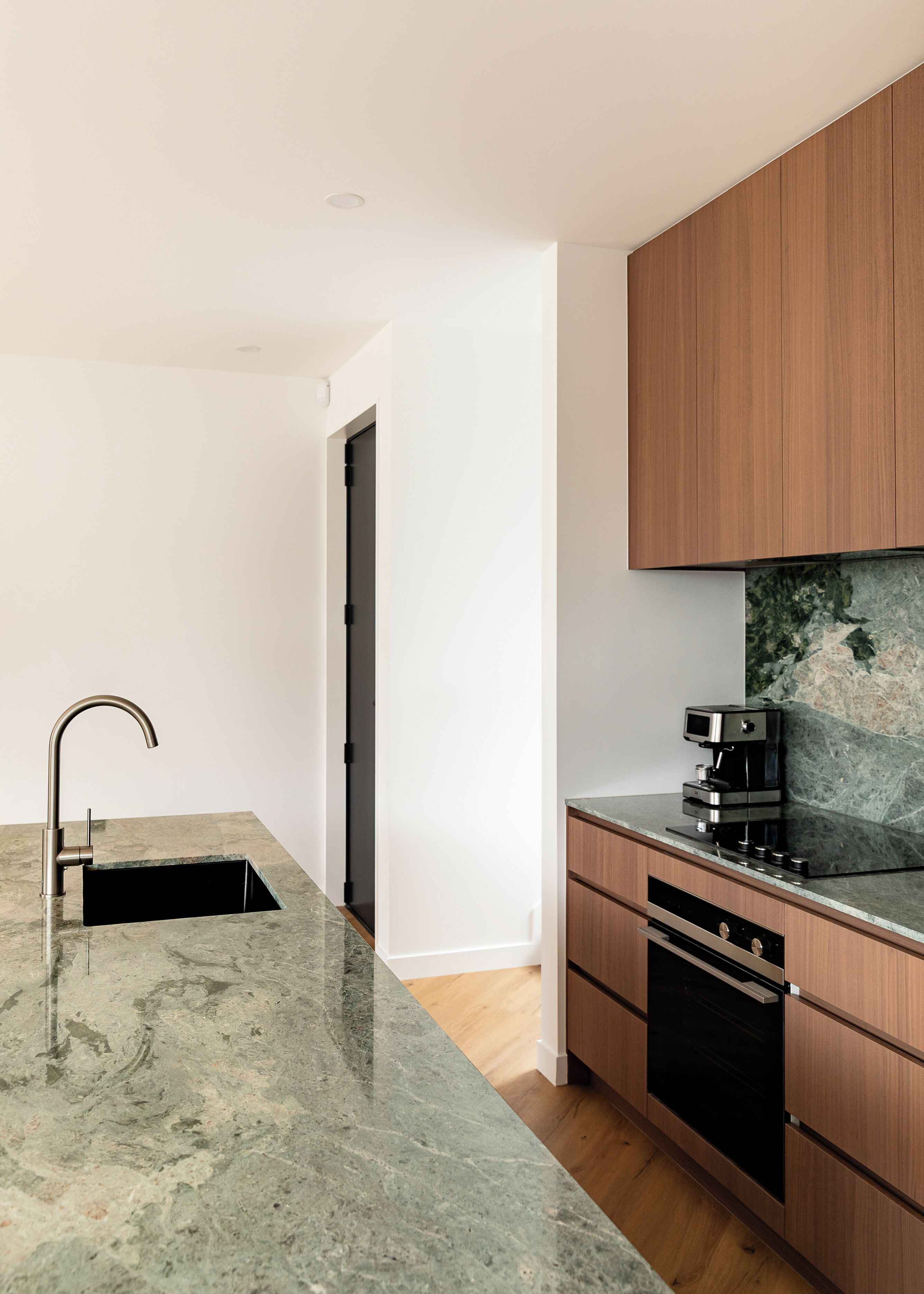 A modern kitchen with a marble countertop, a built-in oven, and wooden cabinets.