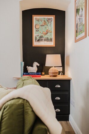 A bedroom with a bed, a nightstand, a lamp, and a framed picture on the wall. - Stunning Garden Flat in Heart of Cheltenham (Cheltenham)