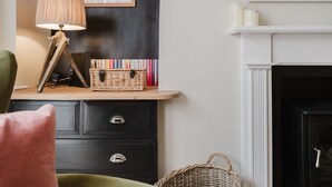 Et værelse med pejs, bogreol, lampe og en kurv af fletværk.