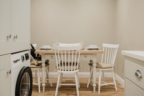 A compact kitchen with a dining table, two chairs, and a washing machine. - Stunning Garden Flat in Heart of Cheltenham (Cheltenham)