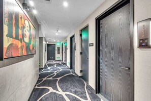 Ein Hotelgang mit Teppichmuster, Türen und einem Ausgangsschild.
