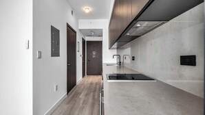A modern kitchen with a central island, a built-in oven, and a stainless steel range hood. - Highrise Condo & Amenities (Miami)