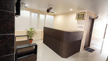 A reception area with a reception desk, a ceiling fan, a potted plant, and a reception sign.
