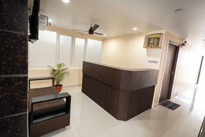 A reception area with a reception desk, a ceiling fan, a potted plant, and a reception sign.