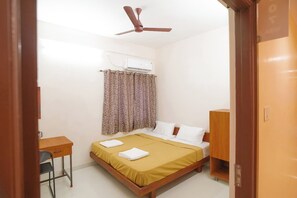 A bedroom with a bed, a desk, a chair, a wardrobe, and a ceiling fan. - Viba Residency (Coimbatore)