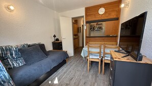 A compact room with a bed, a small dining table, and a kitchenette area. - Studio apartment at the base of the ski lifts, in the center of the resort (Modane)