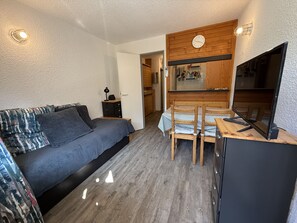 A compact room with a bed, a small dining table, and a kitchenette area. - Studio apartment at the base of the ski lifts, in the center of the resort (Modane)