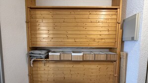 A wooden closet with a sliding door, containing storage boxes and folded blankets. - Studio apartment at the base of the ski lifts, in the center of the resort (Modane)