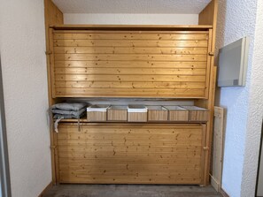 A wooden closet with a sliding door, containing storage boxes and folded blankets. - Studio apartment at the base of the ski lifts, in the center of the resort (Modane)