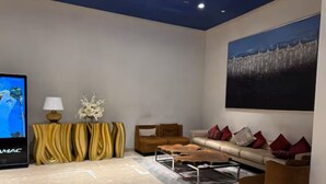 Un salon moderne comprenant un téléviseur à écran plat, un ensemble de canapés, une table basse et un élément décoratif mural.