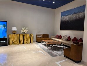 A modern living room with a flat-screen TV, a sofa set, a coffee table, and a decorative wall piece. - Canal View Studio | Balcony + Sofa Bed (Dubai)
