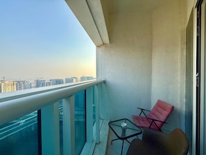 A balcony with a glass railing, two chairs, and a small table. - Canal View Studio | Balcony + Sofa Bed (Dubai)