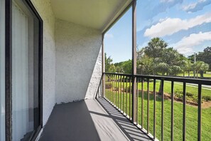 A balcony with a view of a grassy area and trees. - Stylish Furnished Retreat with Modern Comforts (Tamarac)