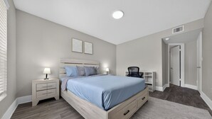 A bedroom with a bed, nightstands, a desk, and a chair. - Stylish Furnished Retreat with Modern Comforts (Tamarac)