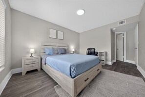 A bedroom with a bed, nightstands, a desk, and a chair. - Stylish Furnished Retreat with Modern Comforts (Tamarac)