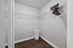 A corner laundry room with a metal drying rack, a white laundry basket, and a wooden floor. - Comfortable Modern Home with Resort Amenities (Tamarac)