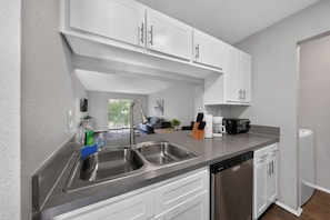 A modern kitchen with white cabinetry, stainless steel appliances, and a dishwasher. - Comfortable Modern Home with Resort Amenities (Tamarac)