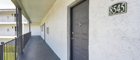 A covered corridor with a door marked '8545' and a balcony with railings.