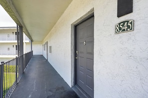 A covered corridor with a door marked '8545' and a balcony with railings. - Comfortable Modern Home with Resort Amenities (Tamarac)