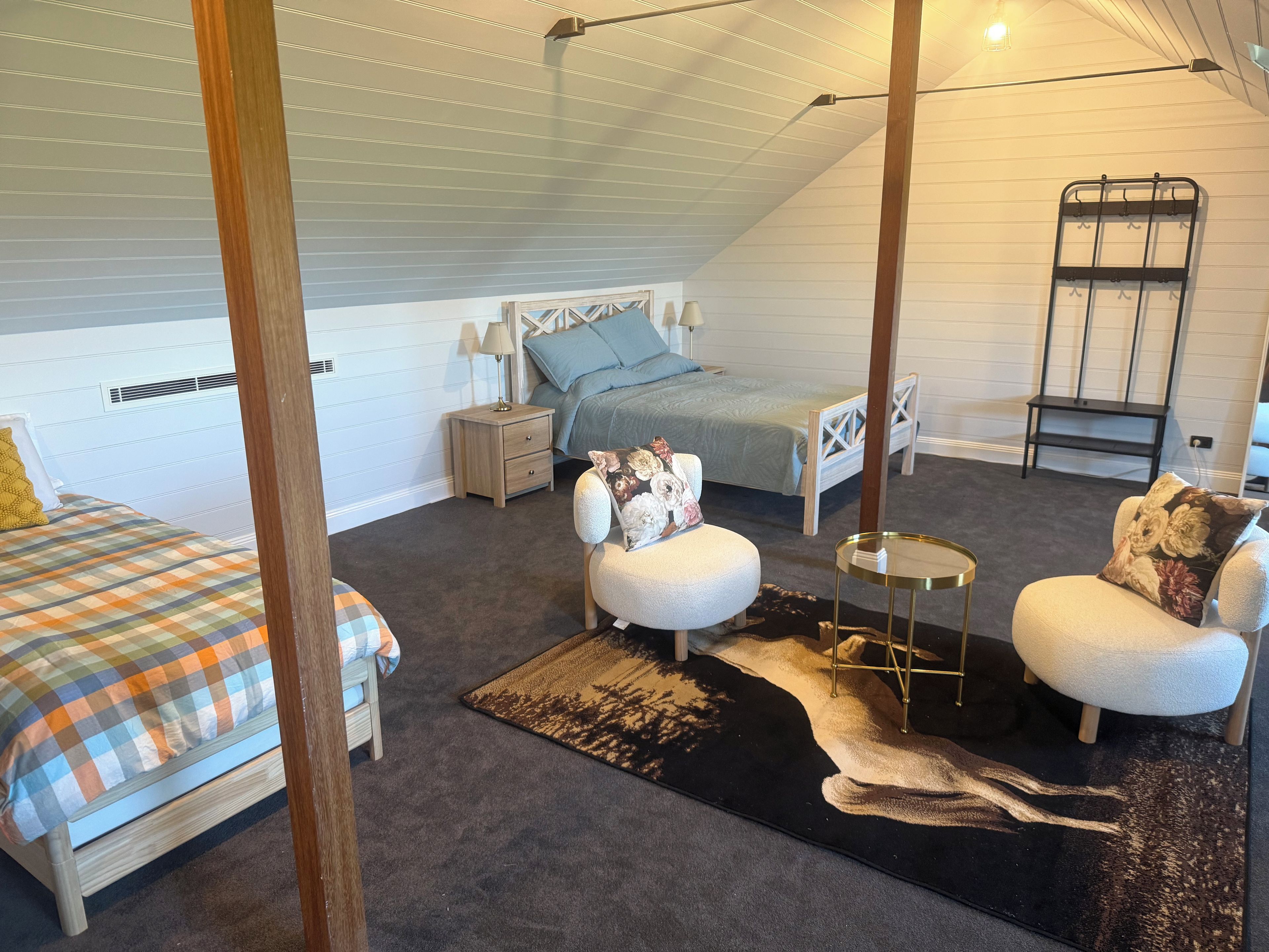 A bedroom with a bed, a nightstand, a chair, a small table, and a ladder against the wall.