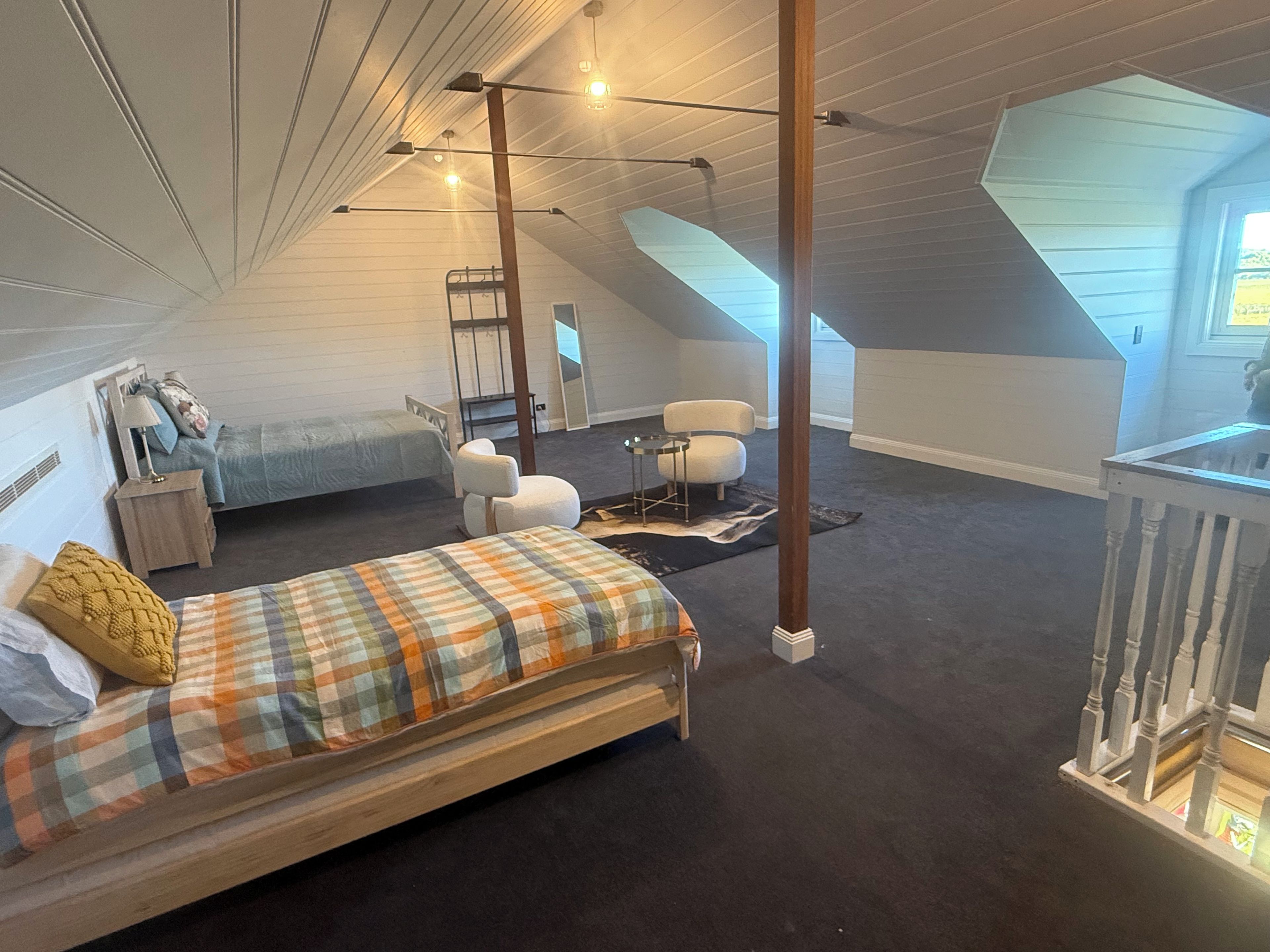 A bedroom with a loft area, a bed, a chair, a desk, and a ladder.