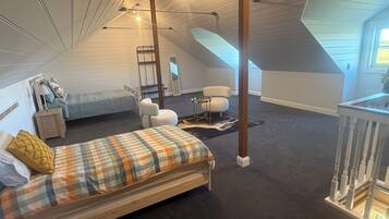 A bedroom with a loft area, a bed, a chair, a desk, and a ladder.