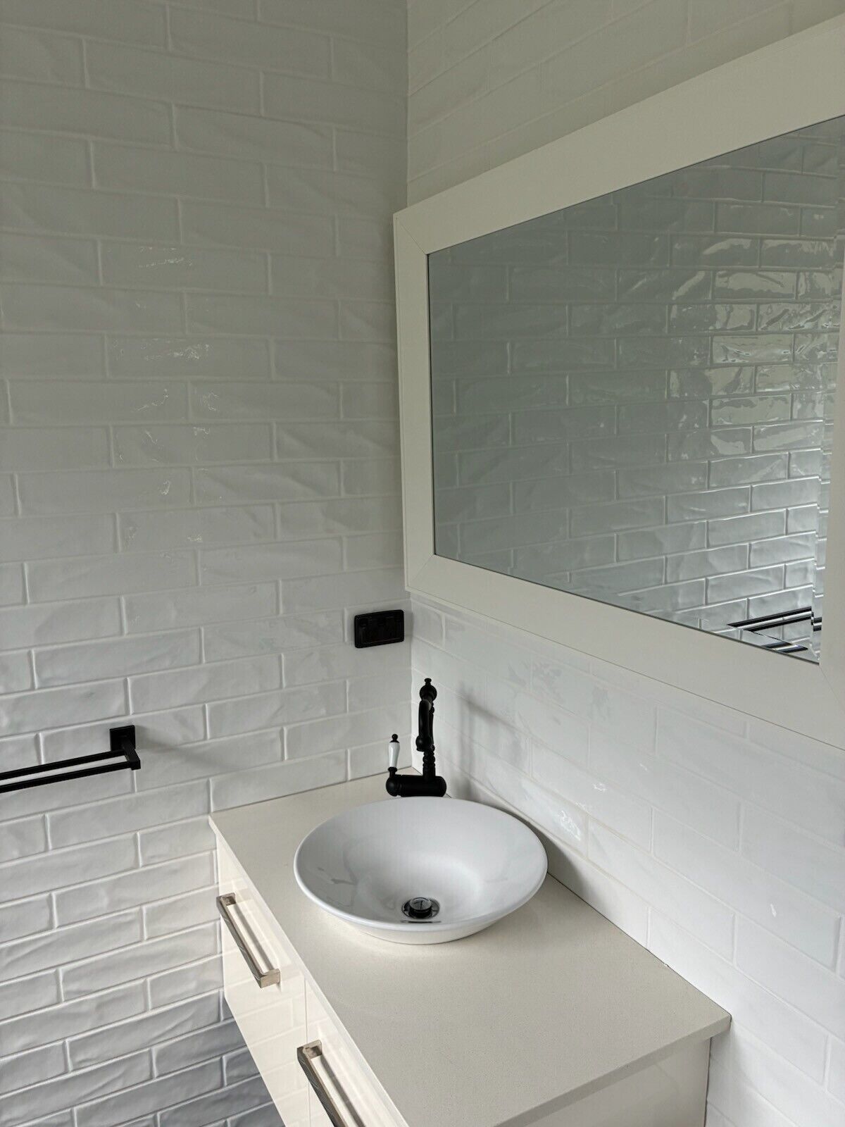 A bathroom with a white sink, a mirror, and a towel rack.