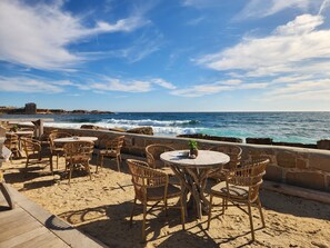 A seaside patio with wicker furniture and a view of the ocean. - Studio apartment with a pool, private parking space, and the ocean within walking distance (Bandol)