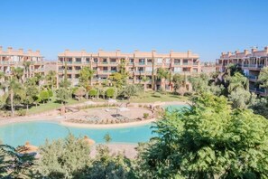 A hotel with multiple balconies, a swimming pool, and lush greenery. - Luxury 2BR with Pool &amp; Garden View Balcony (Marrakech)