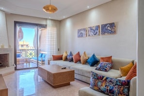 A modern living room with a sofa set, a coffee table, and a fireplace. - Luxury 2BR with Pool & Garden View Balcony (Marrakech)