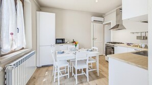 A compact kitchen with white cabinetry, a dining table with chairs, a built-in microwave, and a stove. - Rosa Olivi - Lavaiano (Lavaiano)