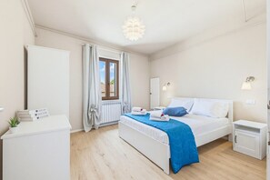 Ein Schlafzimmer mit Bett, Nachttischen, einem Kleiderschrank, einem Fenster mit Vorhängen und einer Deckenleuchte.
