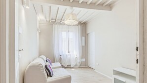 A spacious room with a white sofa, a ceiling light fixture, and a door leading to another room. - Rosa Olivi - Lavaiano (Lavaiano)
