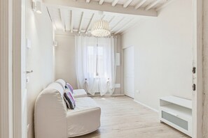 A spacious room with a white sofa, a ceiling light fixture, and a door leading to another room. - Rosa Olivi - Lavaiano (Lavaiano)
