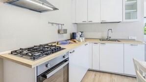 A modern kitchen with white cabinets, a gas stove, and a stainless steel range hood. - Rosa Olivi - Lavaiano (Lavaiano)