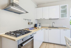 A modern kitchen with white cabinets, a gas stove, and a stainless steel range hood. - Rosa Olivi - Lavaiano (Lavaiano)